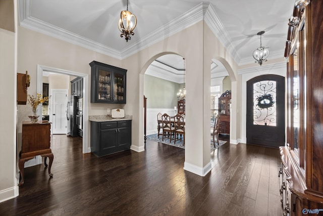 foyer featuring arched walkways, dark wood-type flooring, and a notable chandelier