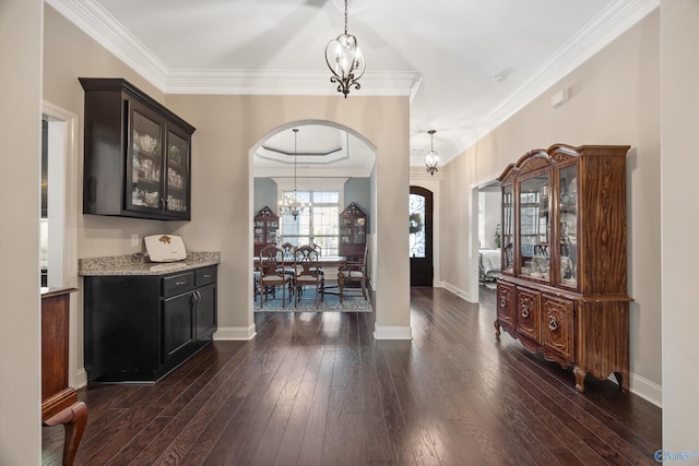 bar with arched walkways, dark wood-type flooring, hanging light fixtures, an inviting chandelier, and crown molding