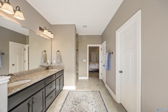 ensuite bathroom with a sink, double vanity, tile patterned flooring, and connected bathroom