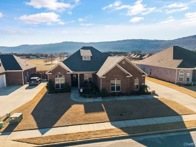 view of front of property featuring driveway, a residential view, a mountain view, and brick siding