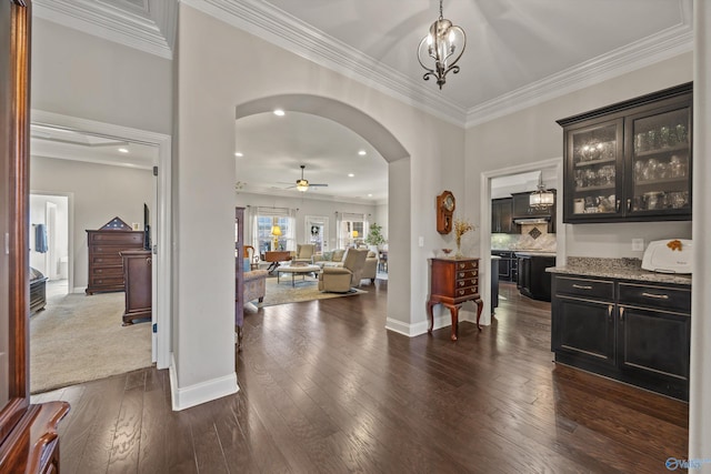 entryway featuring baseboards, arched walkways, dark wood-type flooring, crown molding, and recessed lighting