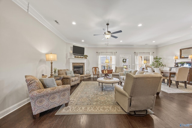 living area featuring a stone fireplace, dark wood-type flooring, visible vents, baseboards, and crown molding