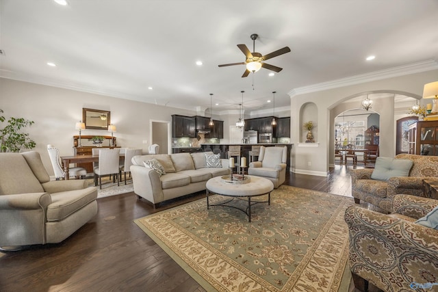 living room with arched walkways, ornamental molding, dark wood finished floors, and recessed lighting