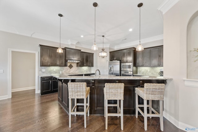 kitchen with dark brown cabinetry, a breakfast bar area, stainless steel appliances, and decorative light fixtures