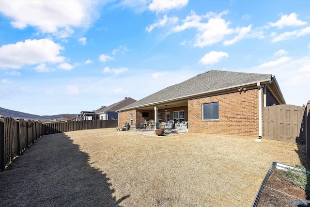 rear view of property with a fenced backyard, roof with shingles, a gate, a patio area, and brick siding