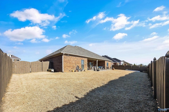 back of house featuring brick siding, a patio, and a fenced backyard