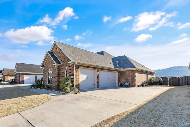 view of front of home with concrete driveway, an attached garage, fence, a mountain view, and brick siding