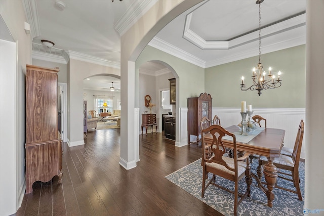 dining space featuring crown molding, arched walkways, wainscoting, and dark wood finished floors