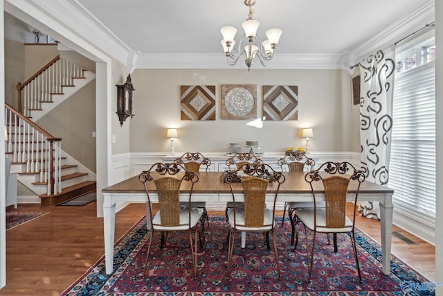 dining space featuring dark wood-type flooring, crown molding, and an inviting chandelier