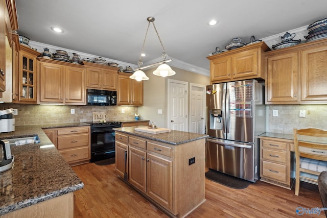 kitchen with crown molding, black appliances, pendant lighting, a center island, and light hardwood / wood-style floors