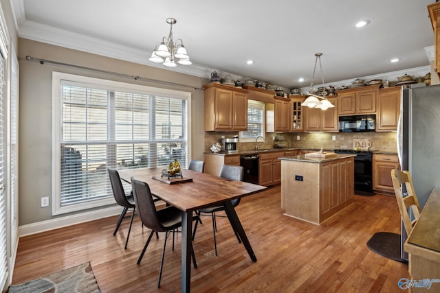 kitchen featuring a center island, black appliances, sink, decorative light fixtures, and a chandelier