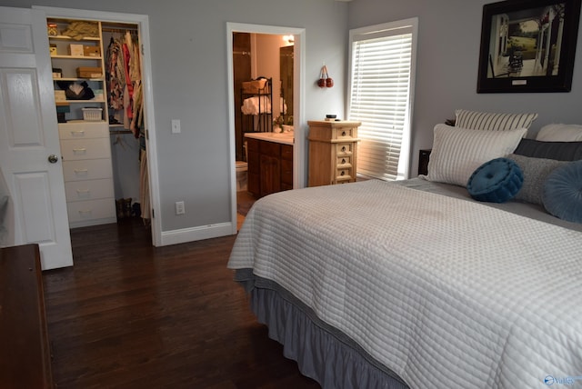 bedroom featuring dark wood-type flooring, connected bathroom, a spacious closet, and a closet