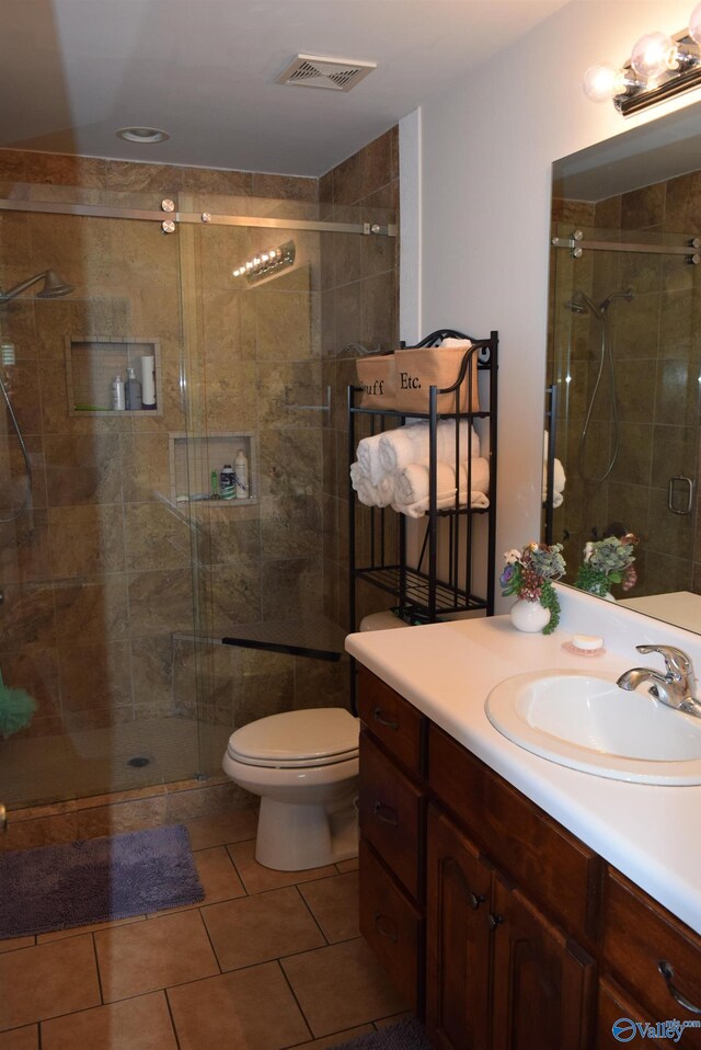 bathroom with tile patterned flooring, walk in shower, toilet, and vanity