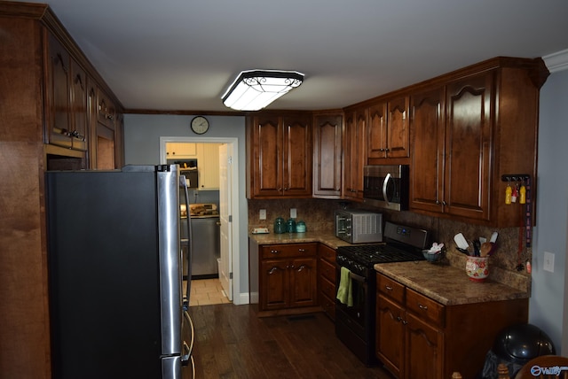 kitchen with dark hardwood / wood-style floors, washer and clothes dryer, stainless steel appliances, ornamental molding, and decorative backsplash