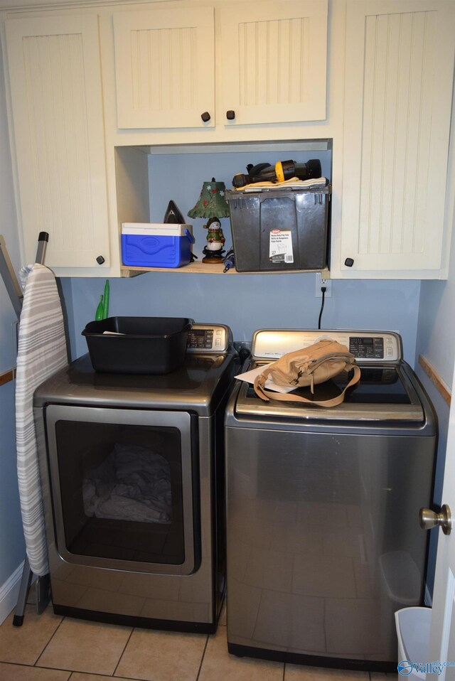 washroom with washing machine and clothes dryer, cabinets, and light tile patterned flooring