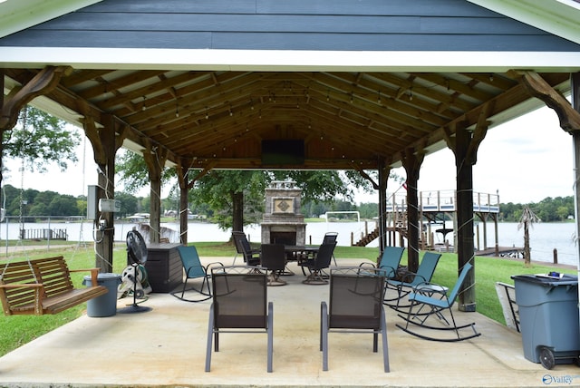 view of patio / terrace featuring a water view, an outdoor stone fireplace, and a gazebo