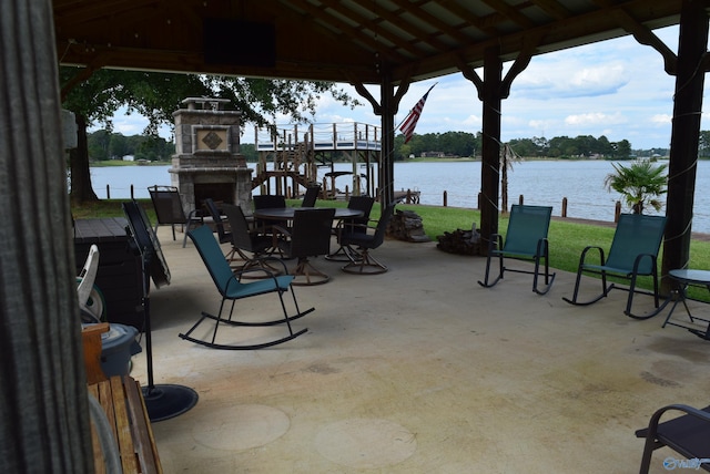 view of patio featuring a water view, an outdoor stone fireplace, and a gazebo