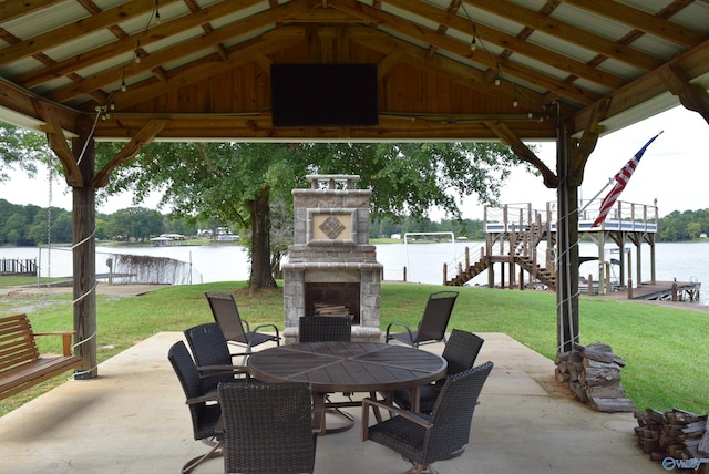 view of patio featuring a water view, an outdoor stone fireplace, and a gazebo