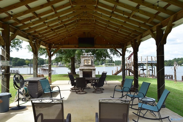 view of patio / terrace with a water view, an outdoor stone fireplace, and a gazebo