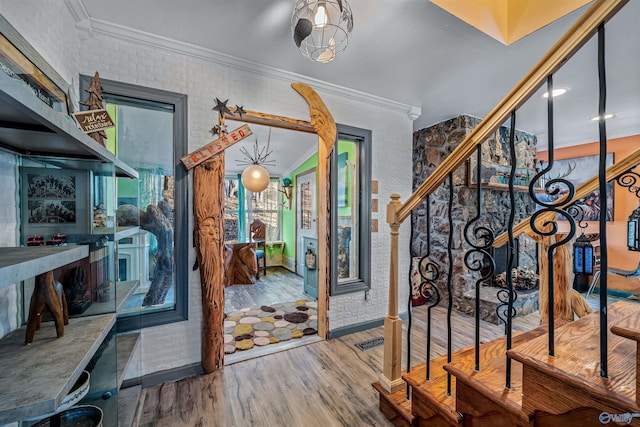 foyer entrance featuring crown molding, brick wall, and hardwood / wood-style floors