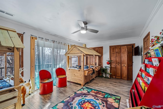 game room with wood-type flooring, ornamental molding, and ceiling fan