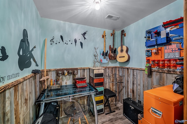 interior space with hardwood / wood-style flooring and wooden walls