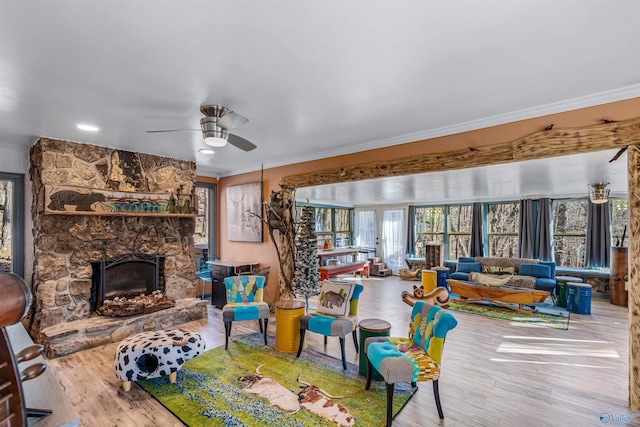 living room featuring ornamental molding, a stone fireplace, and hardwood / wood-style floors