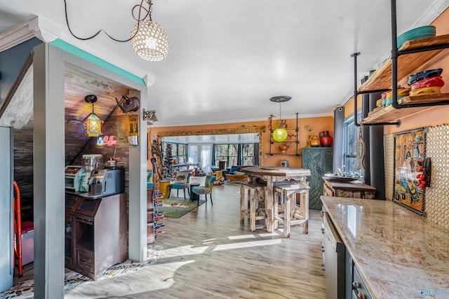 kitchen with crown molding, pendant lighting, light stone counters, and light hardwood / wood-style floors