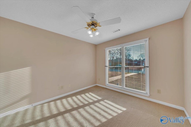 carpeted spare room with a textured ceiling, a ceiling fan, visible vents, and baseboards