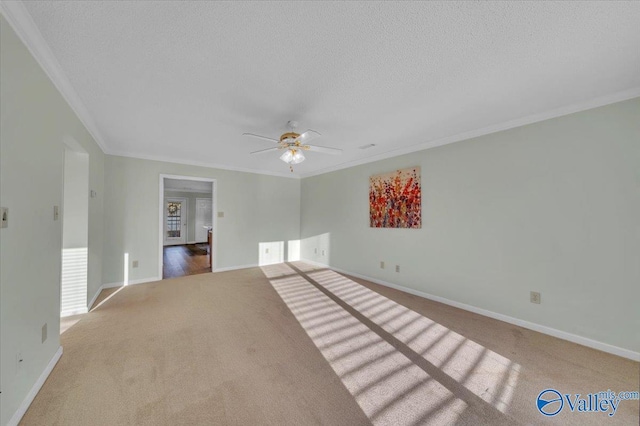 empty room featuring baseboards, a ceiling fan, crown molding, a textured ceiling, and carpet floors