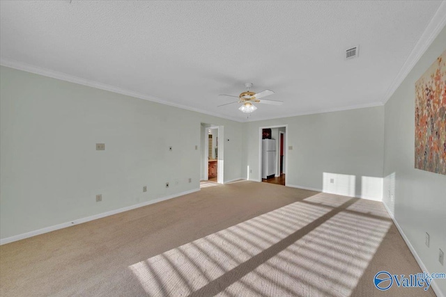 carpeted empty room featuring a textured ceiling, a ceiling fan, visible vents, baseboards, and ornamental molding