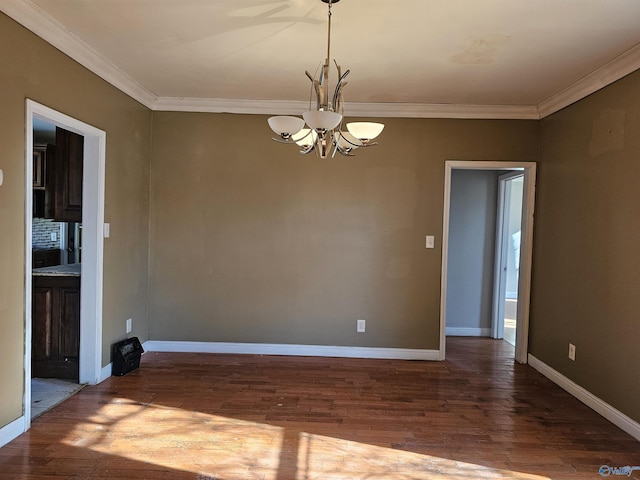 spare room featuring hardwood / wood-style floors, crown molding, and an inviting chandelier