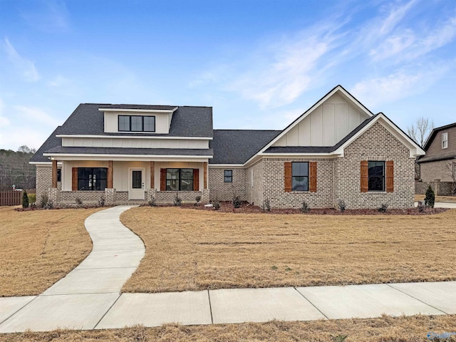 view of front of property with a front yard, board and batten siding, and brick siding