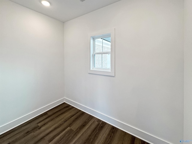 spare room featuring baseboards and dark wood-style flooring