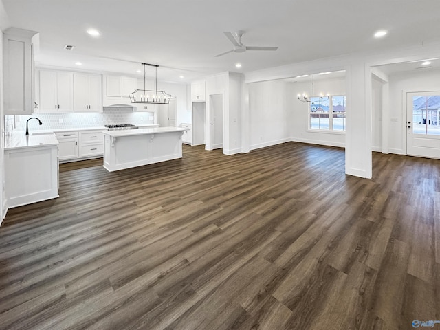 kitchen with dark wood-style floors, light countertops, backsplash, white cabinets, and a sink