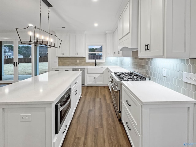 kitchen featuring appliances with stainless steel finishes, a sink, backsplash, and a kitchen island