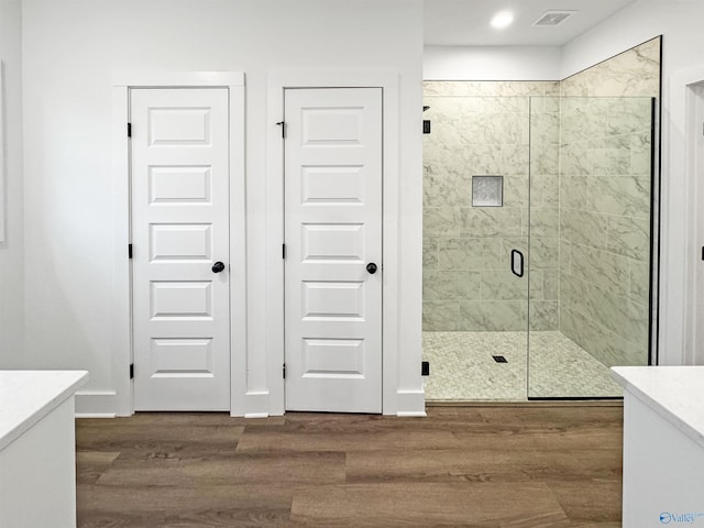 bathroom with wood finished floors, vanity, baseboards, visible vents, and a shower stall