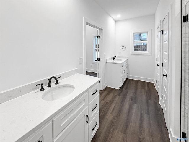 bathroom featuring two vanities, a sink, baseboards, and wood finished floors