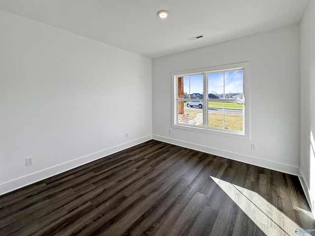 spare room featuring visible vents, dark wood finished floors, and baseboards