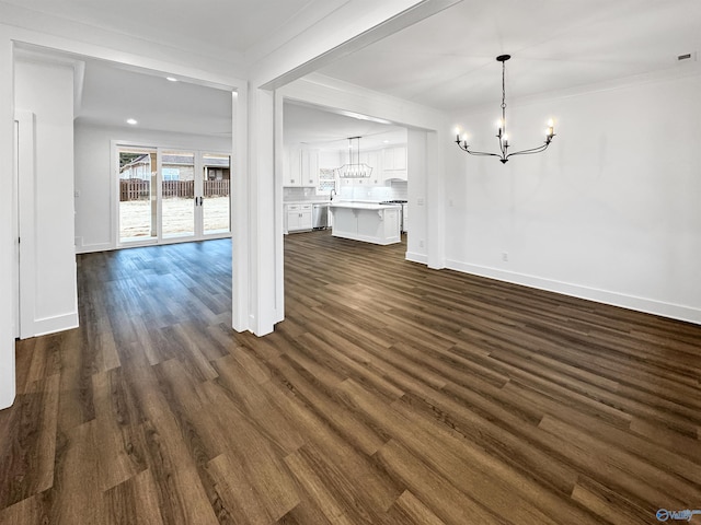 unfurnished living room featuring a chandelier, ornamental molding, baseboards, and dark wood-style floors