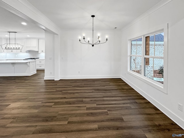 unfurnished dining area featuring a chandelier, ornamental molding, baseboards, and dark wood-style floors