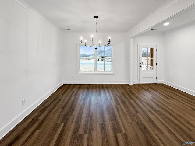 unfurnished dining area featuring dark wood-style flooring, crown molding, baseboards, and an inviting chandelier