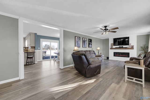 living room featuring a textured ceiling, a large fireplace, light hardwood / wood-style flooring, and ceiling fan