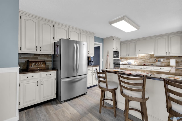 kitchen featuring stainless steel fridge, wall oven, and white cabinetry