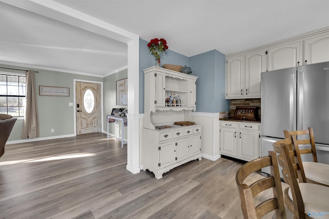 kitchen featuring stainless steel fridge, tasteful backsplash, a textured ceiling, white cabinets, and light hardwood / wood-style floors