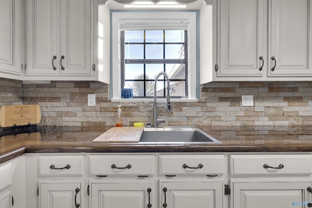 kitchen with decorative backsplash, white cabinetry, sink, and a healthy amount of sunlight