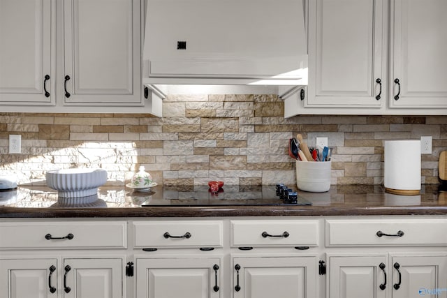 kitchen with white cabinets, backsplash, black electric cooktop, and range hood