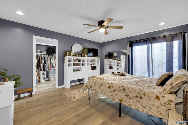 bedroom with ceiling fan, a closet, a textured ceiling, and hardwood / wood-style flooring