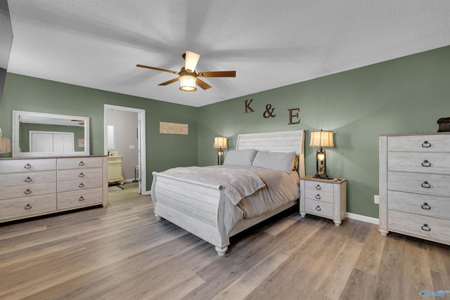 bedroom with ceiling fan, light hardwood / wood-style flooring, and a textured ceiling