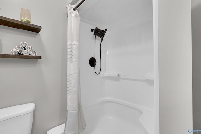 bathroom with a shower with shower curtain and toilet